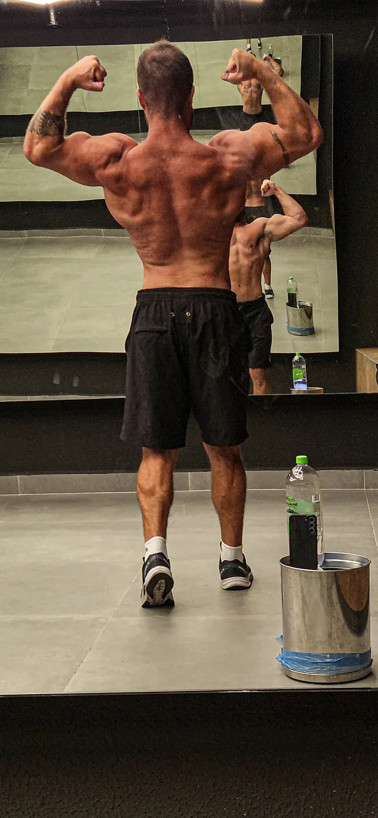 Montinho, personal trainer em Alphaville, em pose no espelho da academia mostrando o desenvolvimento das costas — 4Perform Alphaville