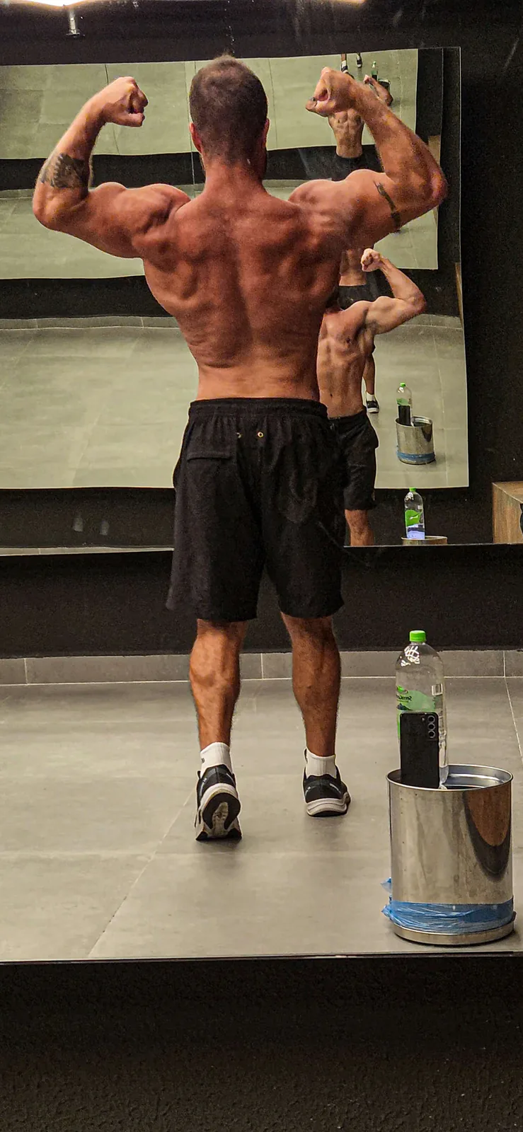 Montinho, personal trainer no Tamboré 2, em pose no espelho da academia mostrando o desenvolvimento das costas